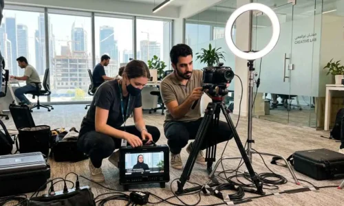 Two individuals collaborating on a video project, adjusting a camera and discussing filming techniques.